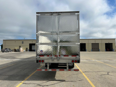 Rear view of a 2027 utility reefer trailer showing diamond plate doors and taillights in a loading yard.