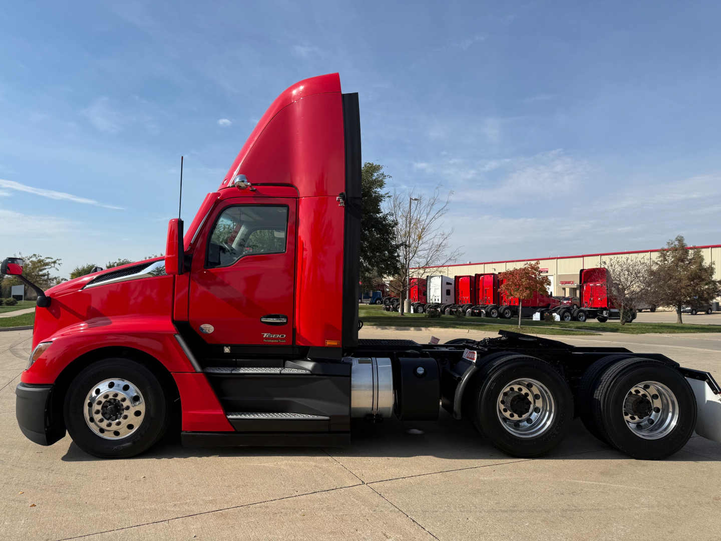 Kenworth T680 conventional daycab truck side profile showing red cab and chassis with dual rear axles.