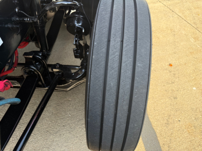 Kenworth T680 truck chassis with front axle area and multi-ribbed steer tire visible in the foreground.