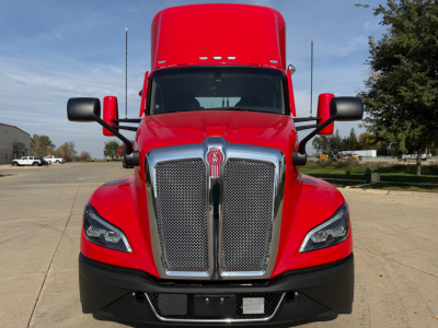 Kenworth T680 front view in red with chrome grille, black bumper, and large sleeper cab. Visible Kenworth emblem on grille.