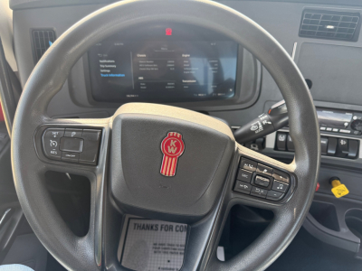 Kenworth T680 truck interior steering wheel and dashboard view showing digital instrument cluster, steering wheel controls, and center stack.