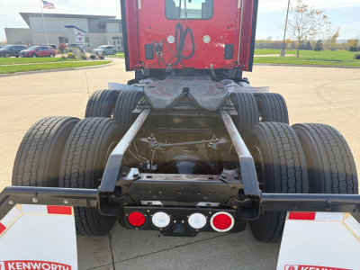 Kenworth T680 chassis and rear view showing fifth wheel and dual rear axles under a red cab, with visible tires and bumper lights.