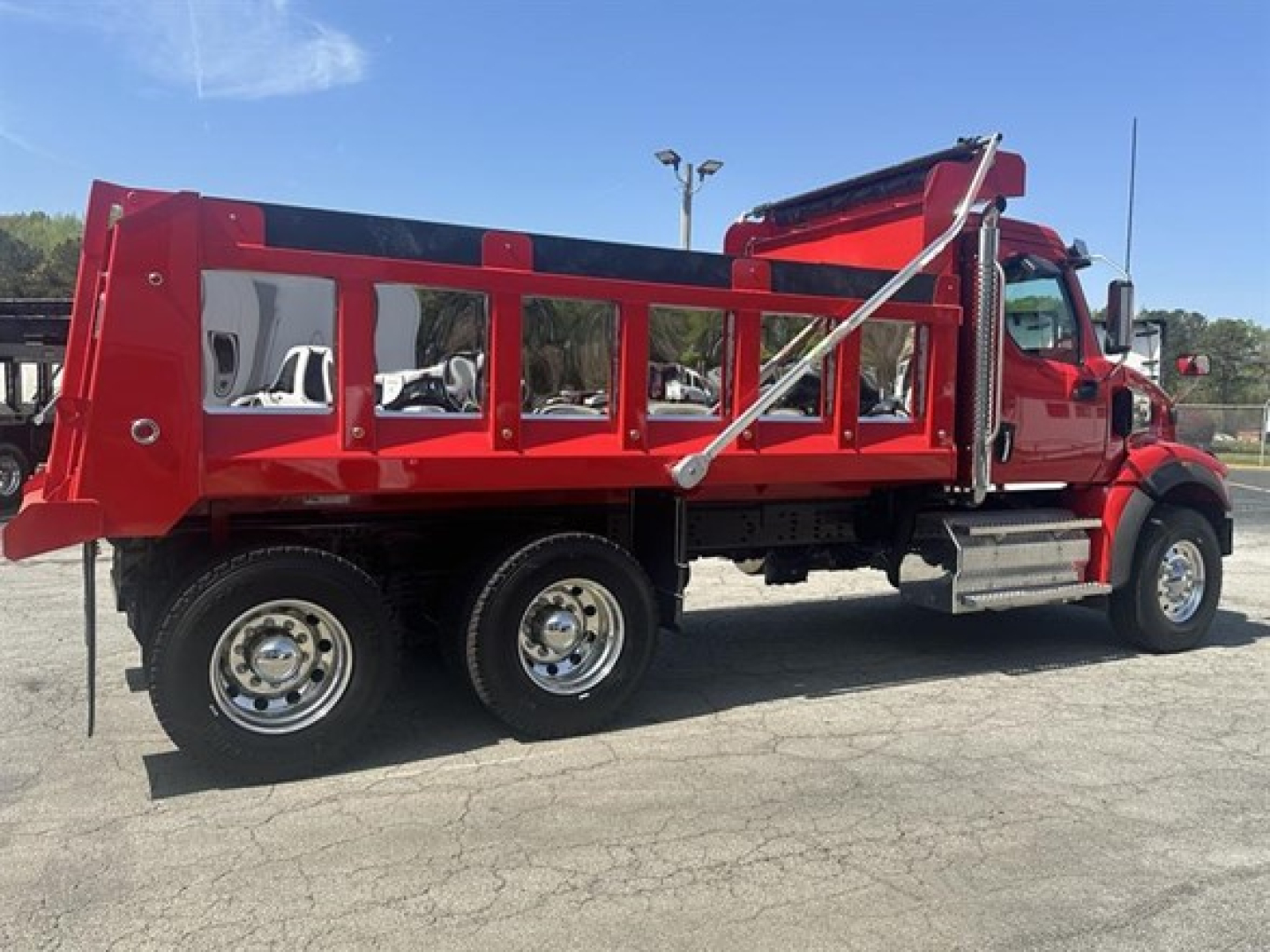 Dump truck side view in red with dual rear axles and metal dump bed, Western Star 47x style labeling not visible.