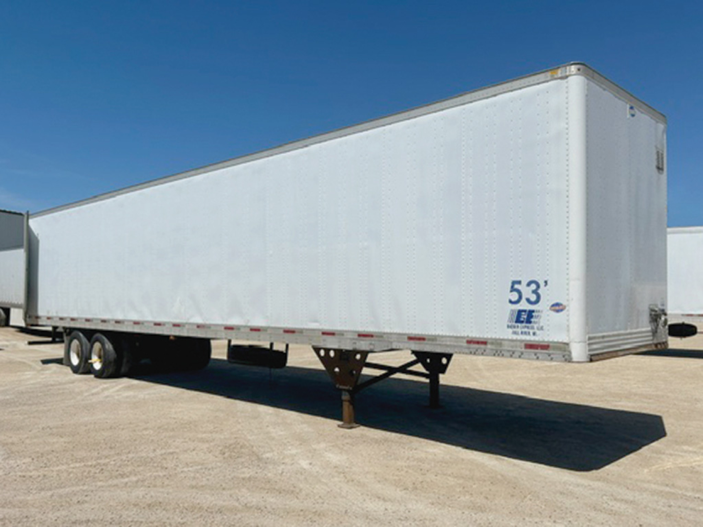 Trailer showing a white 53' Utility box with dual tandem axles at left and landing legs in foreground.