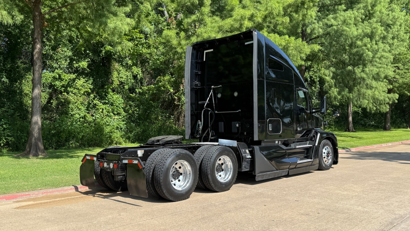 Kenworth T680 tractor from rear-side view showing rear axles and fifth wheel in a parking lot.