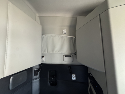 Cab interior of a Kenworth T680 sleeper with storage compartments and control panels visible.