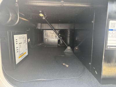Interior of Kenworth T680 sleeper cab storage area showing a small electronic control module mounted on left wall and wiring harness with a hanging connector.