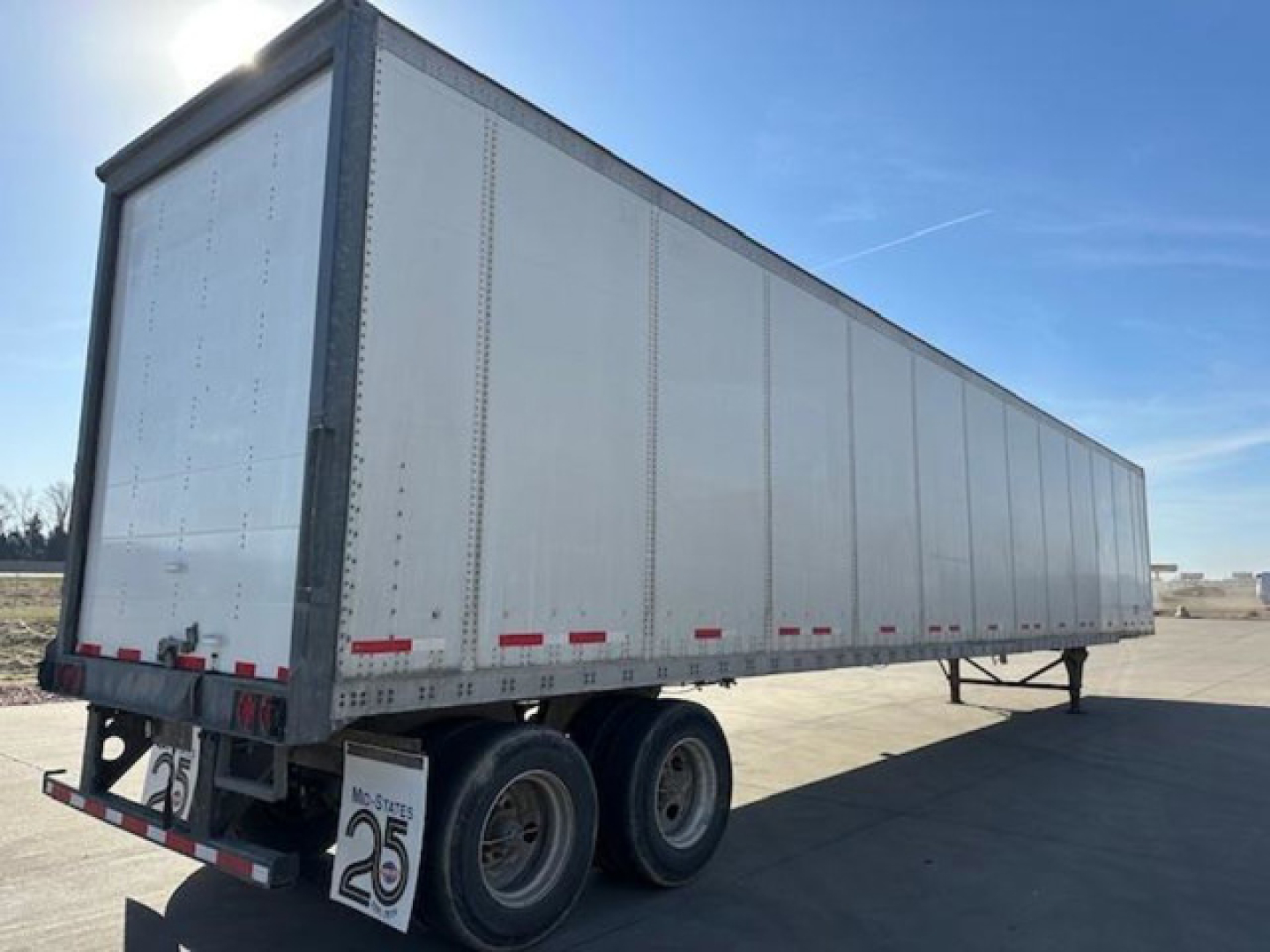 Trailer side view showing a long silver Wabash van trailer with two rear axles and a raised landing gear, stock number U90792 visible.