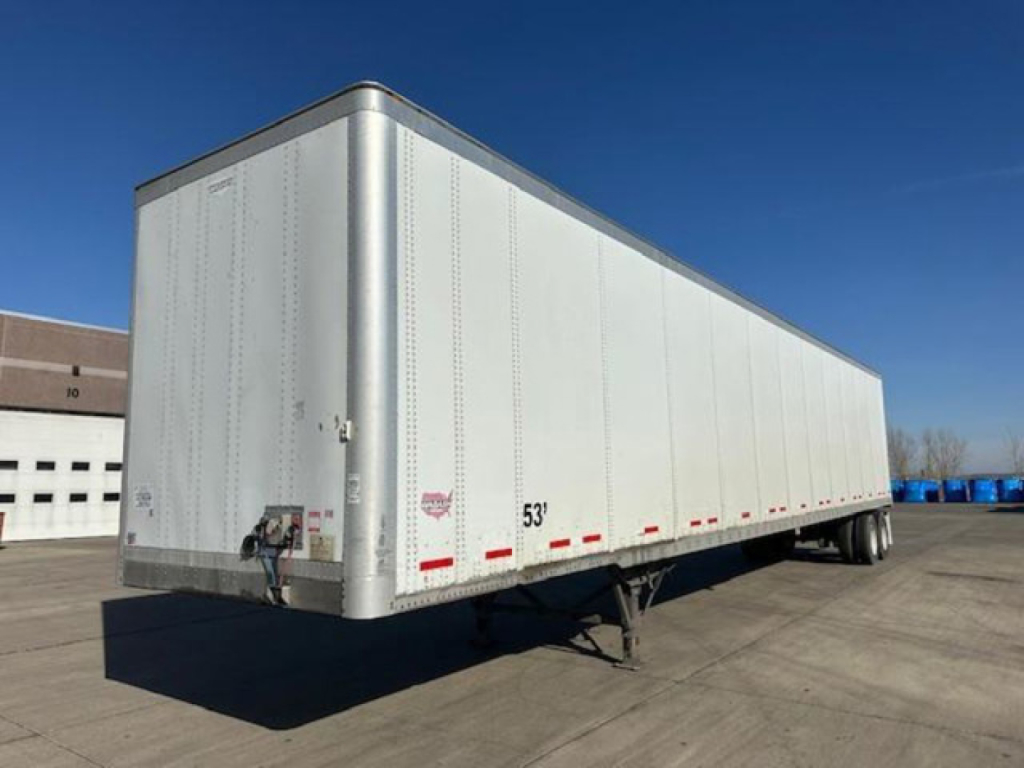 Trailer side view showing a white Wabash van trailer in a parking lot, with rear doors and front landing gear visible.