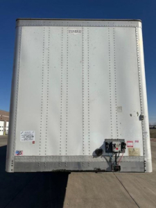 Rear view of a white cargo trailer showing a hitch and small stickers.