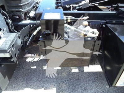 Isuzu NPR-HD chassis components showing hydraulic reservoir and hydraulic lines in engine bay area.