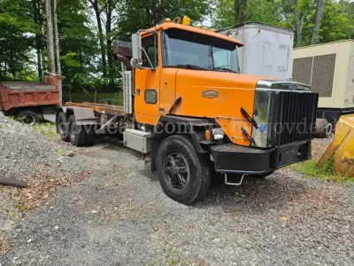 Orange 2009 Freightliner M2 106 dump truck front-left angle showing cab, grille, and side mirrors with black bumper and chrome accents.
