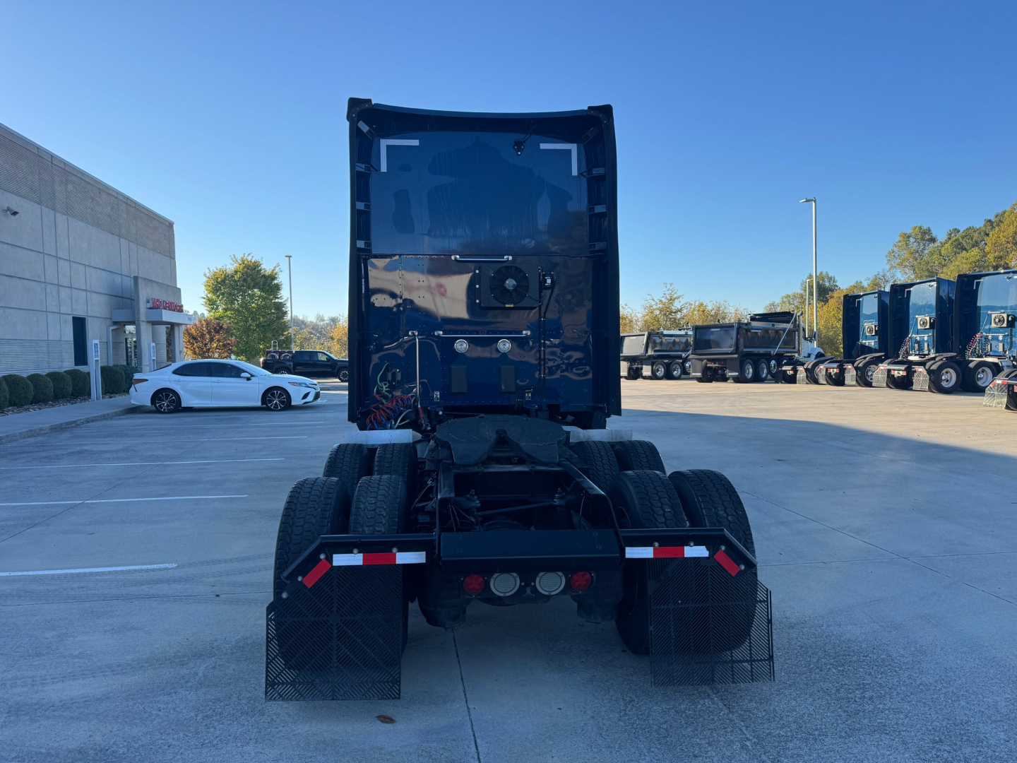 Kenworth T680 tractor rear view showing fifth wheel and dual rear axles with mud flaps and taillights.