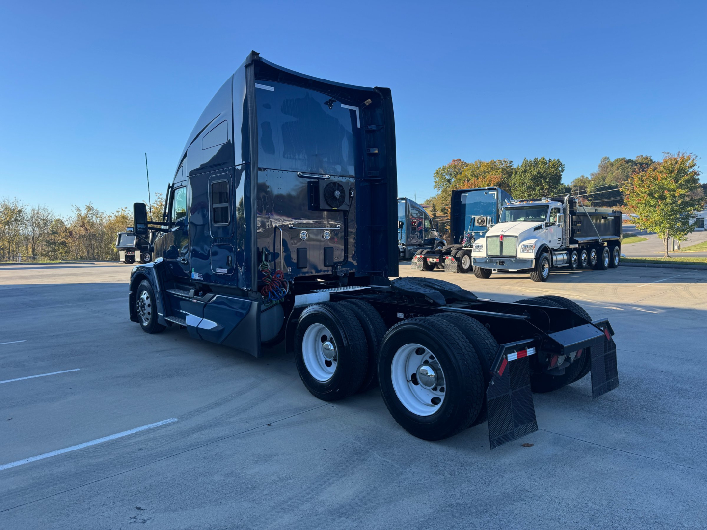 Kenworth T680 tractor with sleeper, rear view showing dual rear axles, fifth wheel, and chrome wheels.