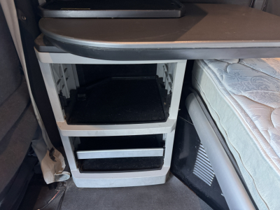Kenworth T680 interior sleeper cab storage area with shelves and drawers visible under a desk surface.