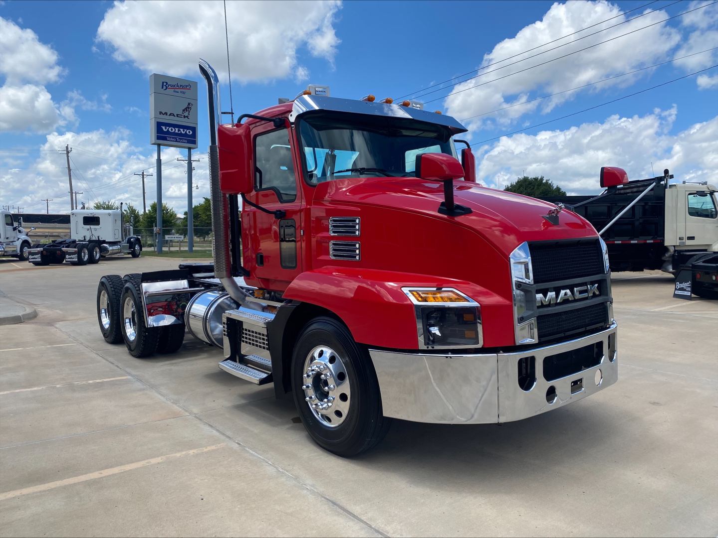 Mack AN64T conventional daycab truck in red with chrome bumper and dual rear axles, showing front grille with MACK and side exhaust.