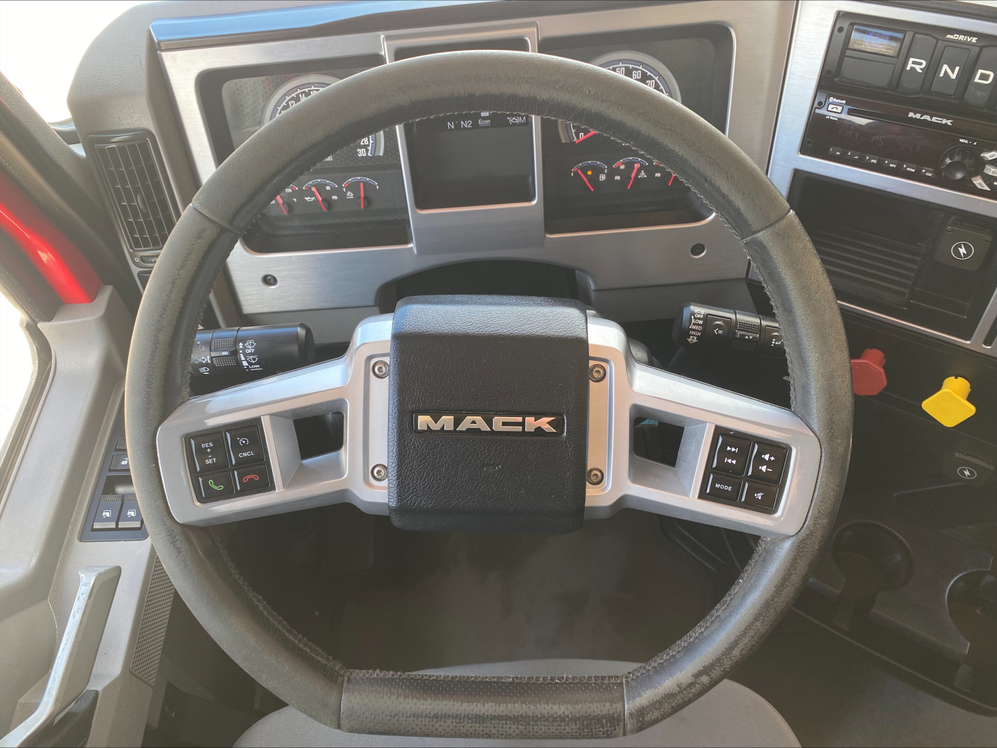 Steering wheel and instrument cluster of a 2021 Mack AN64T conventional daycab truck interior, with Mack logo on the center pad and dashboard controls visible.