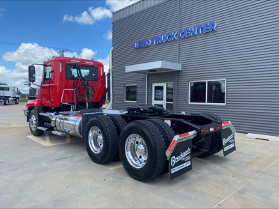 Mack AN64T daycab truck chassis rear view showing dual rear axles and mud flaps at a used truck center.