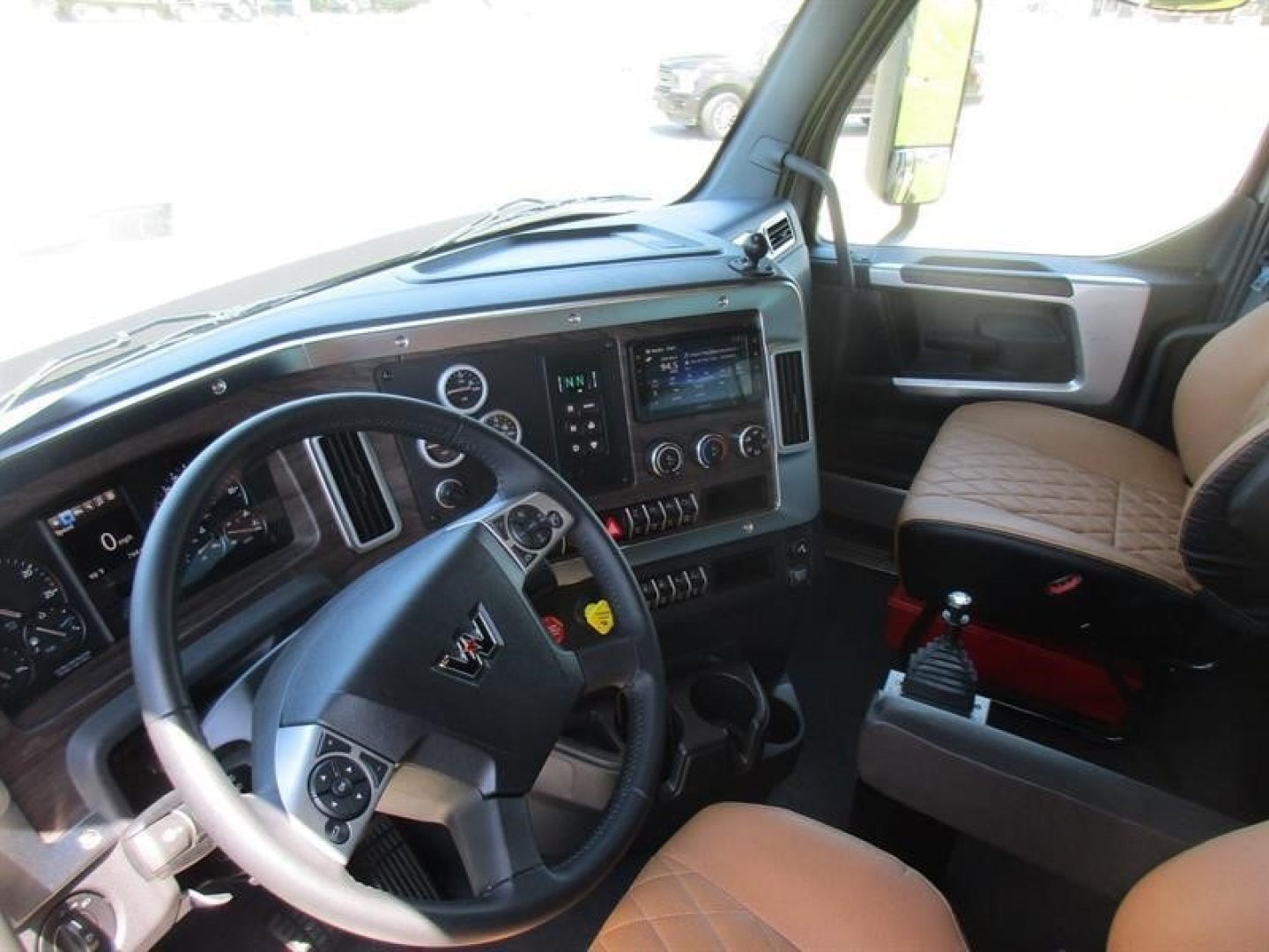 Western Star 49X cab interior showing dashboard with steering wheel, gear shifter, and center console; tan seat upholstery visible.