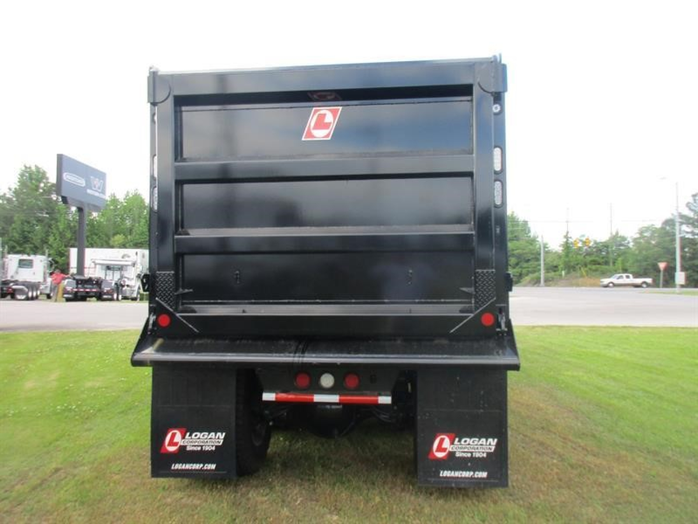 Dump truck bed rear view showing logoed tailgate and mud flaps with Logan branding.