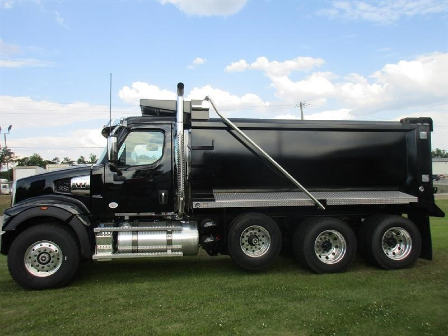 Dump truck side view showing 6x4 configuration with black dump body and chrome fuel tanks, Western Star 49X, VIN 5KKMBWFG4TLWF0305.