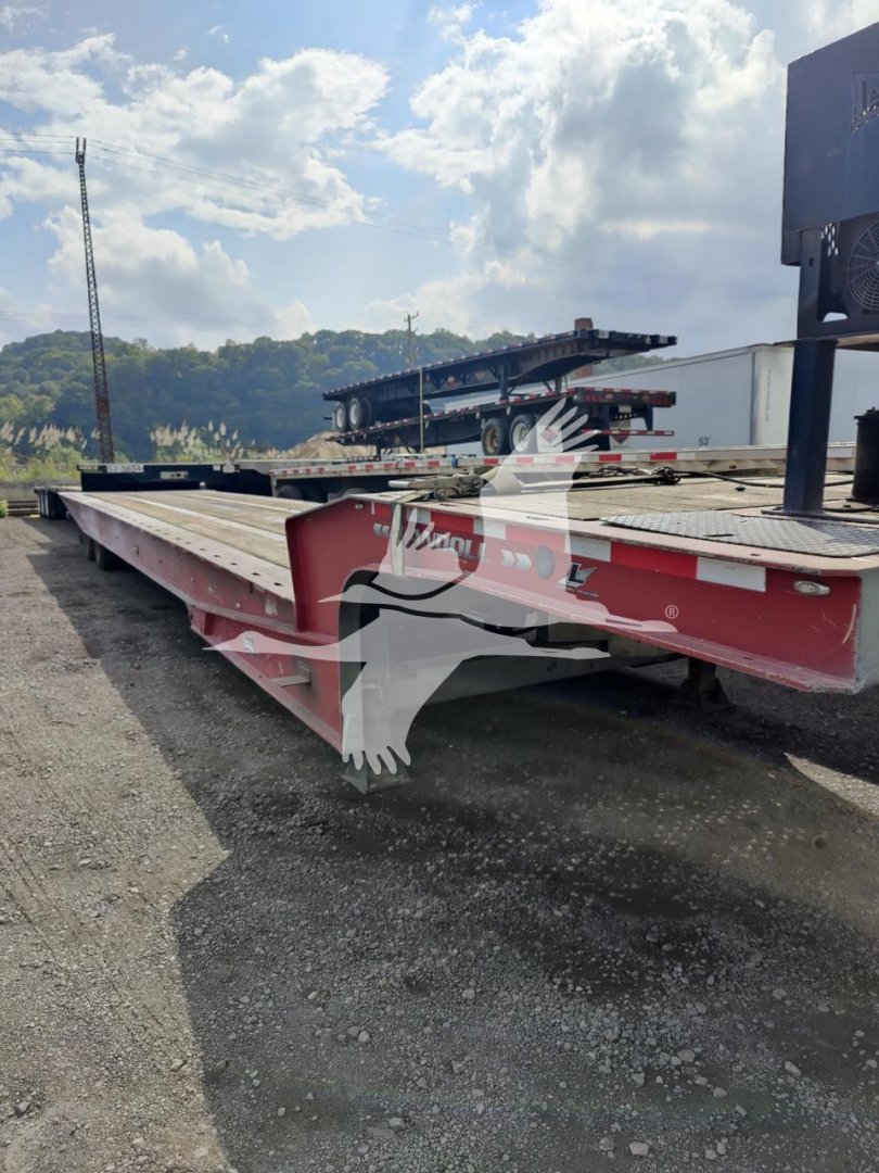 Landoll 440B trailer in side view showing long orange/brick red deck with steel I-beam frame and tandem axle setup.