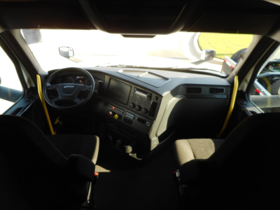 Cab interior of a 2024 Freightliner Cascadia truck showing steering wheel, dashboard, and center console.