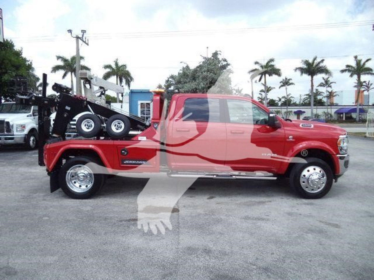 2024 Ram 5500 Laramie crew cab pickup with a heavy-duty winch tow setup on a flatbed and palm trees in background.