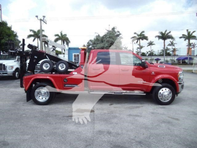 2024 Ram 5500 Laramie crew cab pickup with a heavy-duty winch tow setup on a flatbed and palm trees in background.