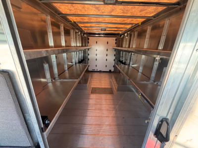 Interior of a new Harbinger S524 step van cargo area with metal shelving along both sides and a white rear door at the far end.
