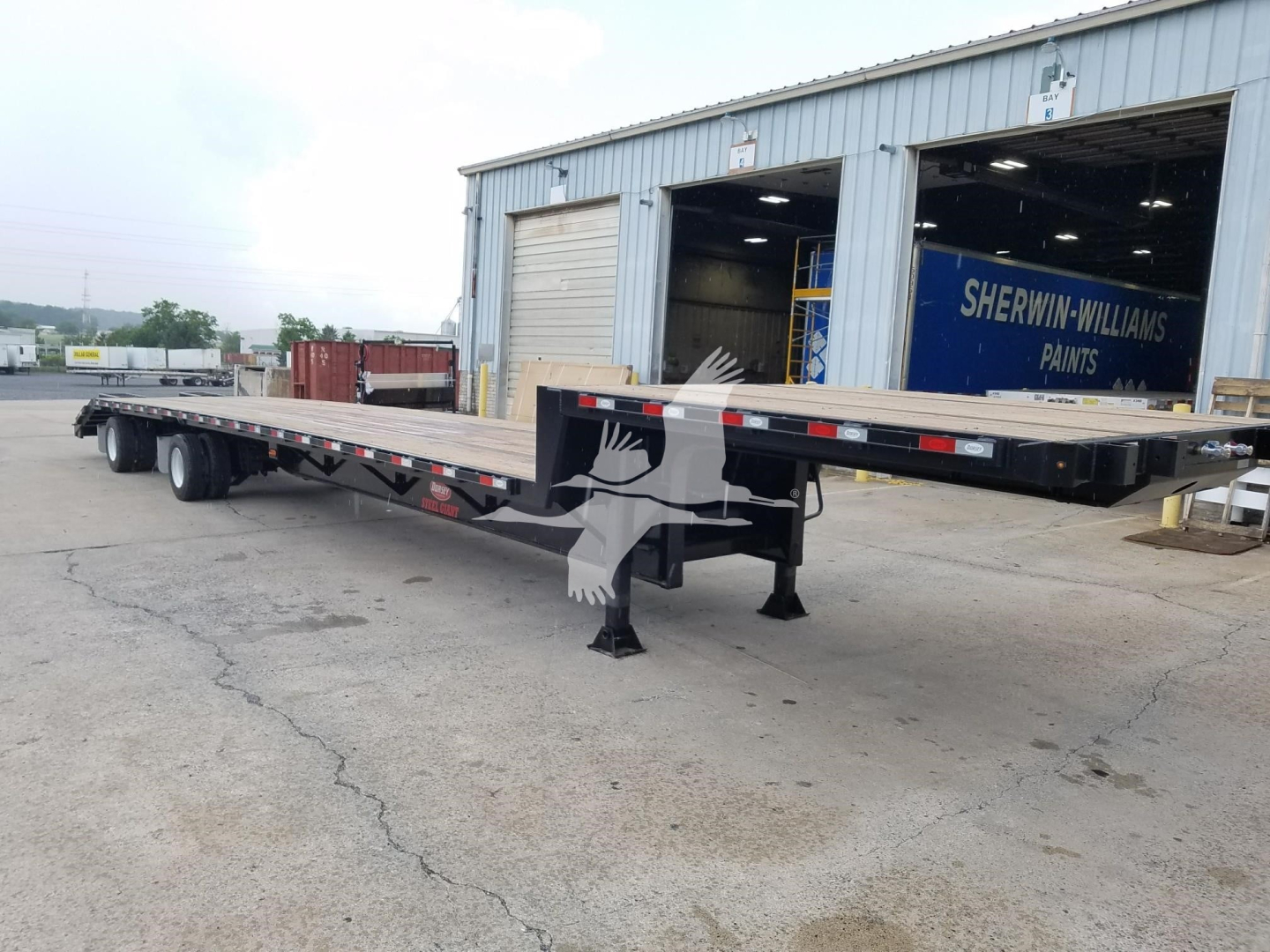 Trailer: New 2026 Dorsey beavertail drop deck trailer showing long flatbed with dual rear axles and gooseneck front, parked in yard near a Sherman-Williams building.
