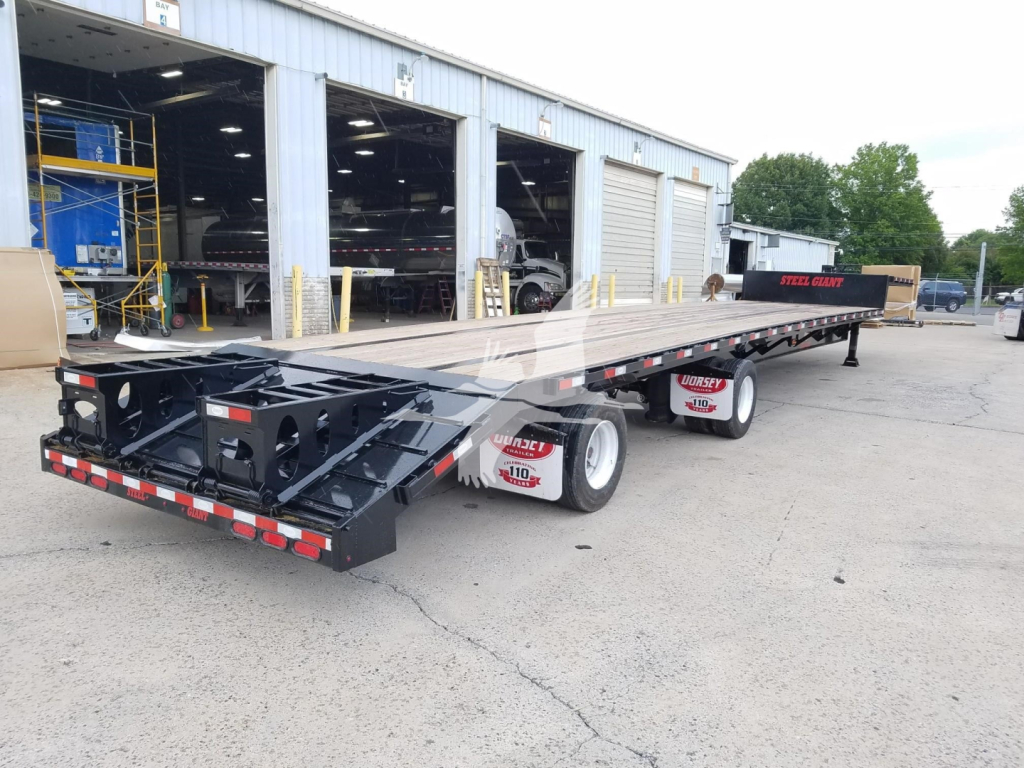 New 2026 Dorsey Beavertail trailer in a parking lot showing a long deck and multiple axles with white rims and black undercarriage.