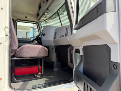 Cab interior of a 2020 Mack Anthem daycab showing steering wheel, dashboard, and seat with a red toolbox under it.