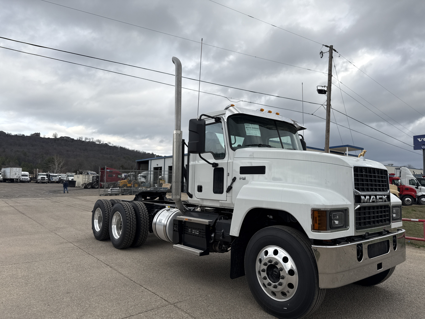 Mack PI64T conventional daycab truck in white, sideview with dual rear axles, large vertical exhaust stack, chrome bumper, and factory wheels visible.