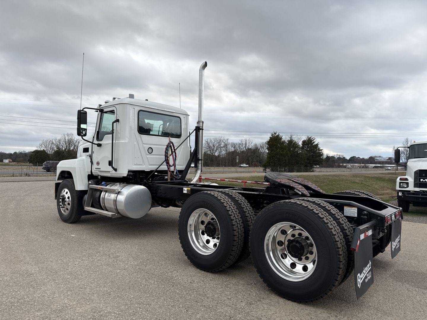 Truck chassis showing rear axles and dual wheels, with exhaust stack and fuel tank visible on the left side; no visible text on the truck components.