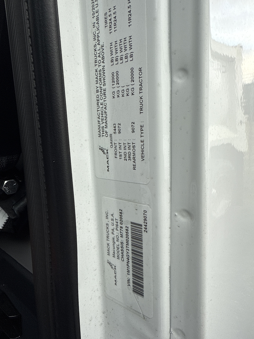 Label plate on Mack PI64T showing vehicle data: manufacturer tag with VIN, model, and specifications; close-up view of side door label with barcodes.