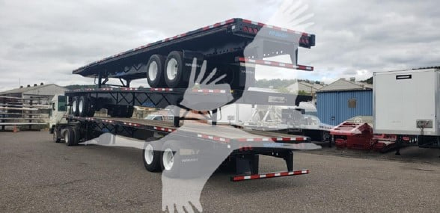 Flatbed trailer with stacked air slider and dual rear axles, appears used, side view with overhangs and support stands.