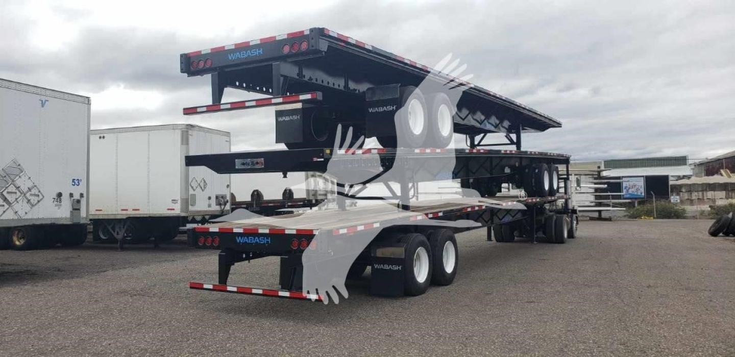 Wabash steel air slider trailer with tandem axles and flatbed ramps, side profile visible in an open lot.