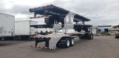 Wabash steel air slider trailer with tandem axles and flatbed ramps, side profile visible in an open lot.
