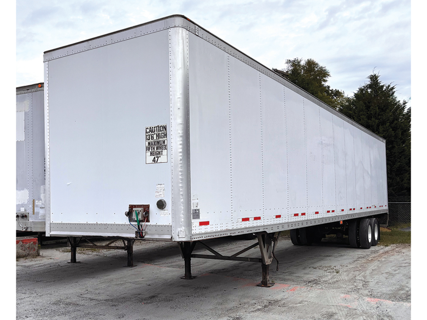 Trailer side view showing a white 2016 Wabash DuraPlate van trailer with landing legs and dual rear wheels.