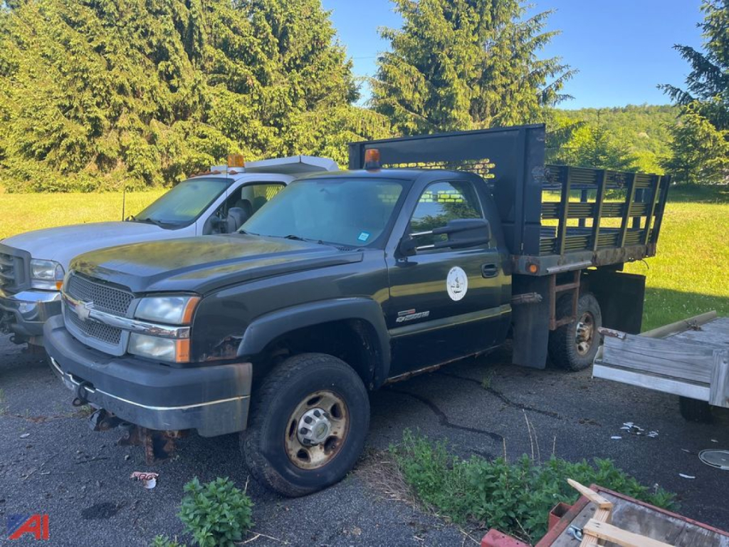 Chevrolet Silverado 2500HD stake truck in dark color, side view with flatbed/stake bed, front bumper, wheel well, and dual rear wheels visible.