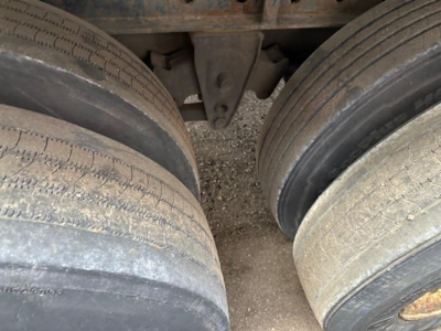 Trailer wheels close-up showing dual rear axles and suspension mount of a 2015 Manac 48' steel flatbed.