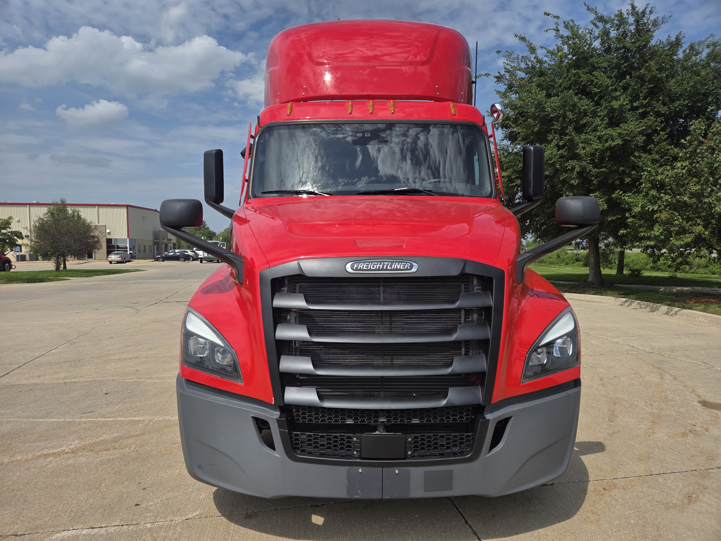 Freightliner PT126064S Daycab front view showing bold grille and cab tilt with red paint and black mirrors.
