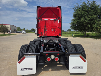 Rear view of a Freightliner PT126064S Daycab truck chassis showing dual rear axles, fifth-wheel area, and white mud flaps with Freightliner logos.