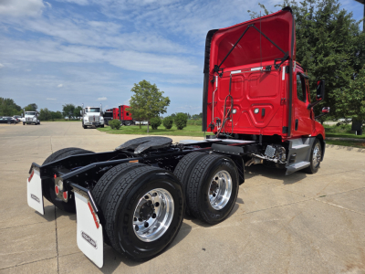 Truck rear view showing cab with red exterior in raised position, dual rear axles, chassis with absent trailer, chrome wheels, white mud flaps.
