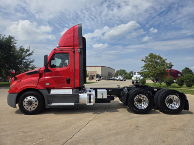 Side view of a red Freightliner PT126064S Daycab truck with the cab raised; shows a chassis without a trailer, dual rear axles, and chrome fuel tanks.