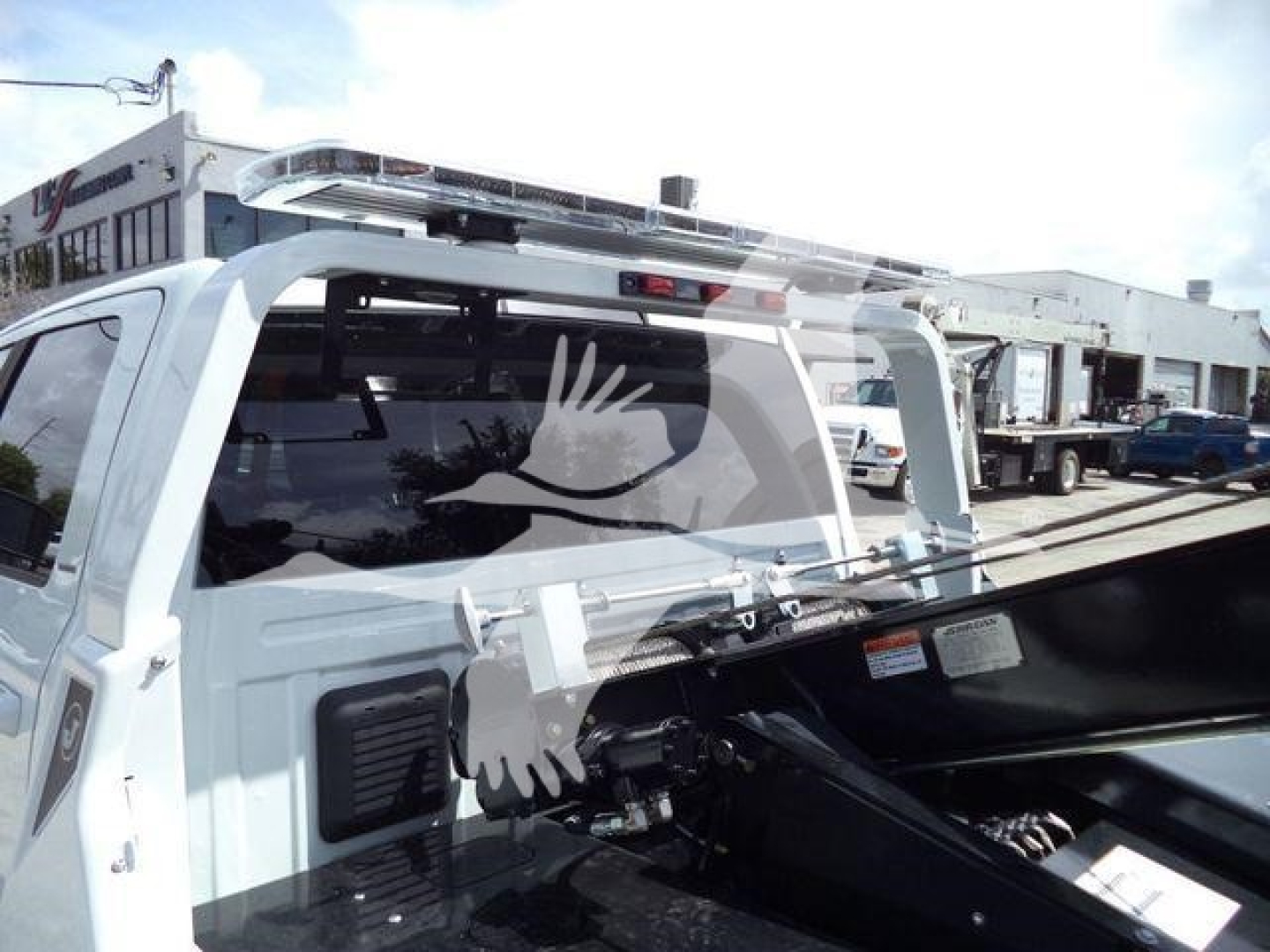 Ram 5500 Laramie pickup truck cab rear and open hood in showroom lot; winch category listing context visible in background.