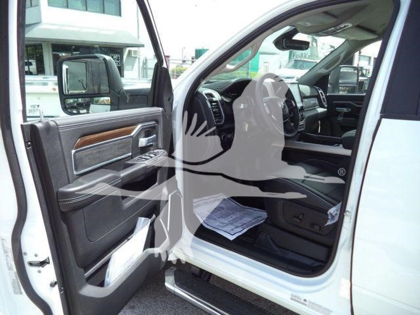 Truck interior showing front driver-side door open, Ram 5500 dashboard and steering wheel visible; partial view of white exterior and side step.