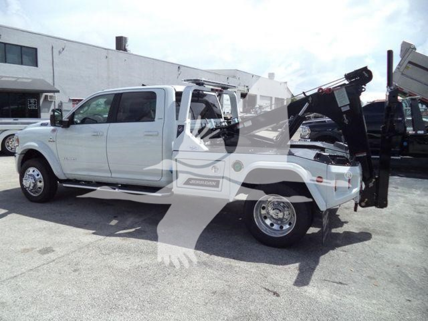 Ram 5500 Laramie pickup truck with utility winch equipment mounted in back, side view showcasing extended crew cab and bed attachment.