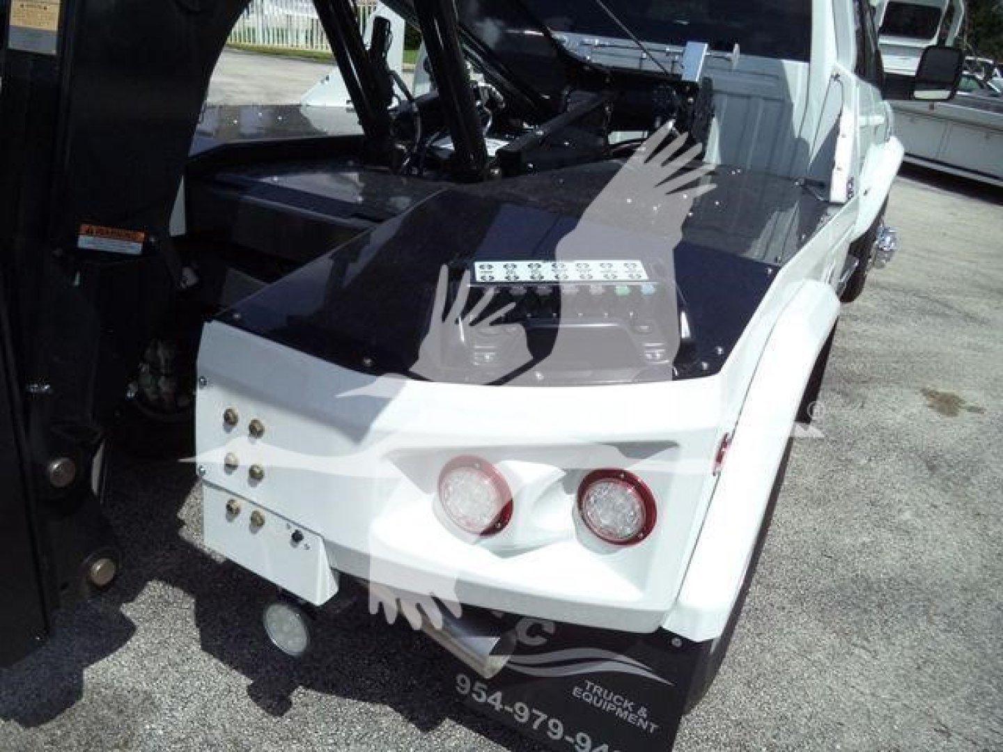 Ram 5500 Laramie winch truck rear view with white bumper and two circular taillights, black tonneau cover, and winch equipment visible in bed area.